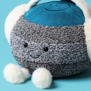 Jellycat Amuseables Sports Cariss Curling Stone zoomed in view of the smiling face. Blue handle, grey granite with white fluffy boots and ear muffs