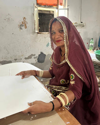 Woman in traditional attire working at a table in an indoor setting.