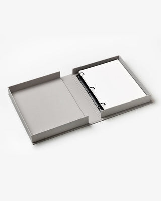 Open gray box with a black ring binder and plain white sheets inside on a white background