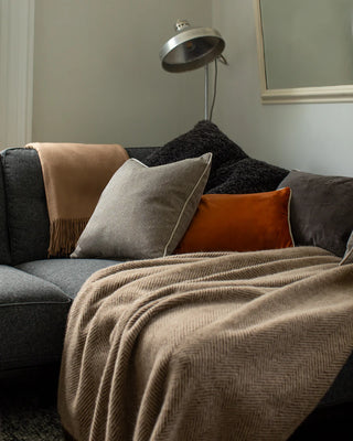 Gray sofa with colorful cushions and a blanket in a cozy living room setting.