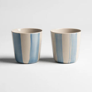 Two ceramic cups with blue stripes on a light gray background