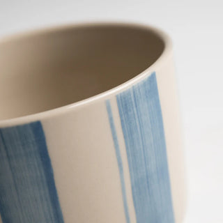 Close-up of a ceramic mug with blue stripes on a white background