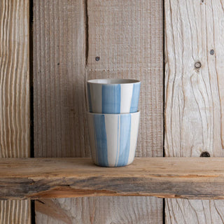 Two ceramic cups with blue and white stripes on a wooden surface and background