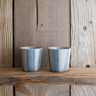 Two blue and white striped ceramic cups on a wooden surface with a rustic wooden background.