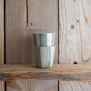 Two stacked green & white striped handless mugs on a wooden shelf
