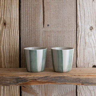 2 green and white striped beakers on a wooden shelf