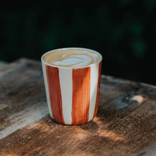 Striped ceramic cup with a latte art design on a wooden surface