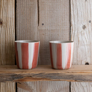 Two striped ceramic cups on a wooden surface with a rustic wooden background