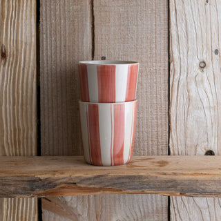Stack of red and white striped ceramic cups on a wooden surface with a wooden background