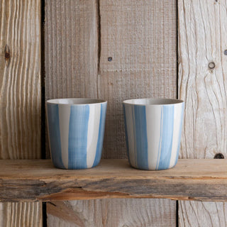 Two striped ceramic cups on a wooden surface with a rustic background