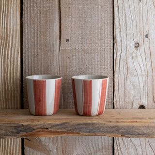 Two striped ceramic cups on a wooden surface with a rustic wooden background