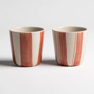 Two ceramic cups with red and white stripes on a light gray background