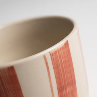 Close-up of a ceramic mug with red stripes on a light background