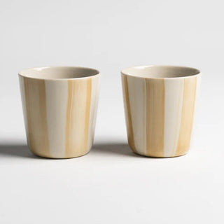 Two wooden cups with a striped design on a light gray background