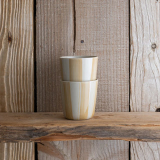 Two stacked ceramic cups on a wooden surface with a rustic wooden background