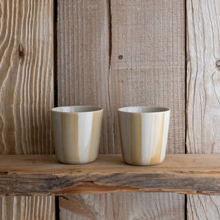 Two ceramic cups with striped design on a wooden surface and background