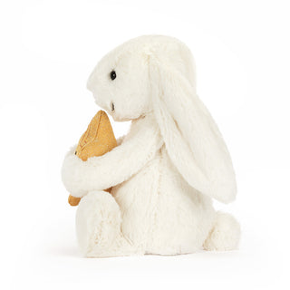 Side view of a White plush bunny holding a gold star on a white background