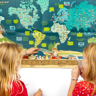 Two young girls playing with dinosaurs at the bottom of the Dinosaur TImeline and world map against a white wall
