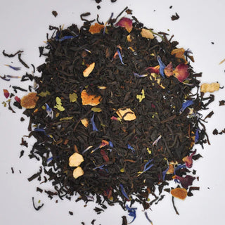 Spice blend with black tea leaves and colorful spices on a white background