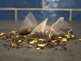 Tea bags with loose tea leaves on a dark surface
