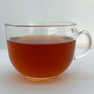 Clear glass mug filled with a tea on a white background