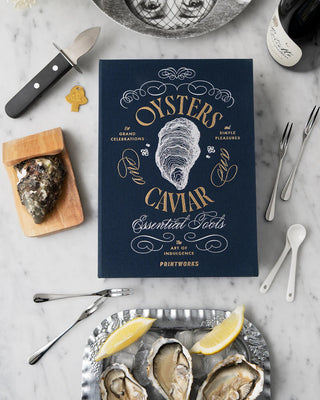 Oysters & Caviar display book lying flat on a worktop surrounded by oysters, utensils and champagne