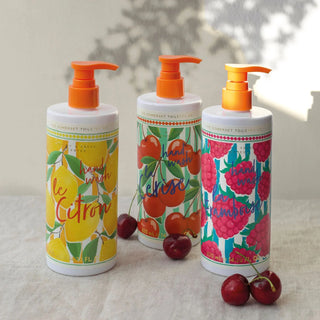 Three bottles of hand wash with colorful labels and orange pumps on a light surface.
