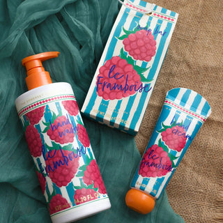 La Framboise range with soap bar packaging, hand wash and hand cream. All blue and white stripe packaging with a raspberry motif placed against a fabric and hessian background