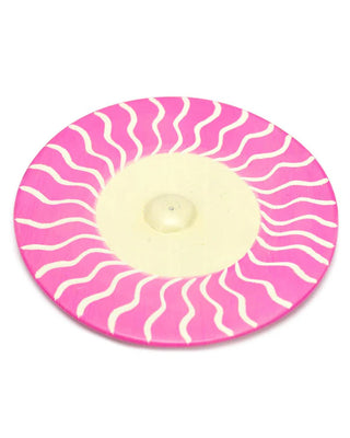 Pink and white striped circular incense holder on a white background