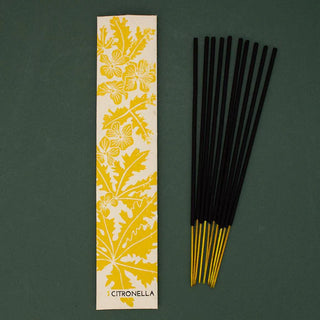 Incense sticks with a yellow citronella leaf patterned packaging on a green background
