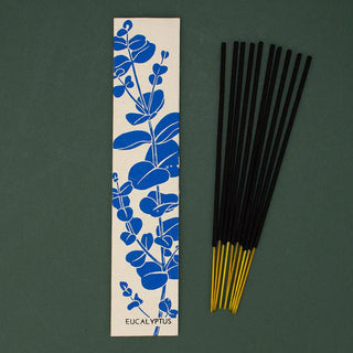 Incense sticks with a blue eucalyptus design on a beige strip against a green background