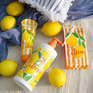 Le Citron Range hand soap, soap bar and hand cream against a fabric background with lemons