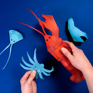 Hands constructing a 3d paper model of a lobster