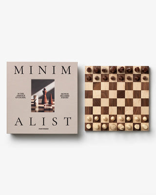 Book titled 'Minimalist' next to a wooden chessboard on a white background