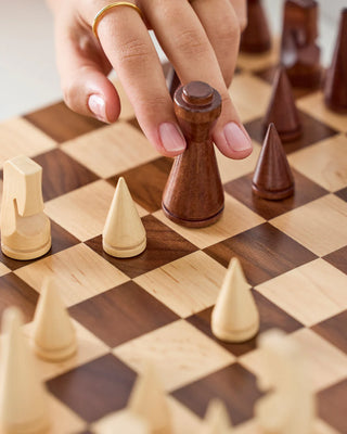 Hand moving a chess piece on a wooden chessboard