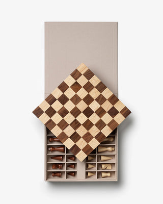 Wooden chessboard with pieces in a box on a beige background
