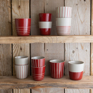 Set of red and white striped ceramic cups on wooden shelves.