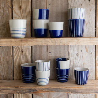 Set of blue and white striped ceramic cups on wooden shelves.