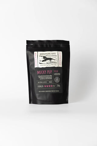 A black bag of Mucky Pup coffee grounds with a white logo and pink and white text against a white background