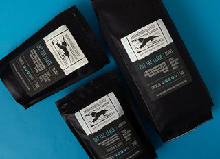 Three black coffee packages with labels on a blue background