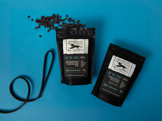 Two black coffee bags with labels on a blue background
