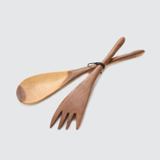 Wooden spoon and fork salad servers set on a light gray background