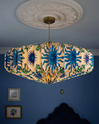 Ceiling light shade with colorful green & blue design with lizards against a blue wall