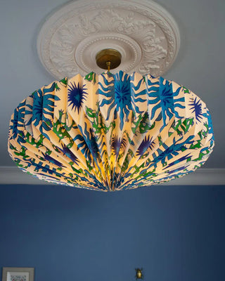 Colorful ceiling light shade with blue and green patterns against a blue wall.