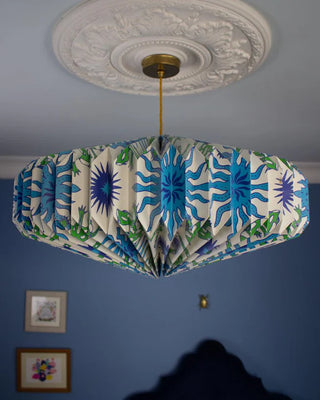 Origami Ceiling light shade with a colorful blue & green lizard pattern against a blue wall.