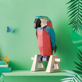 3d Paper parrot on a paper 3d wooden perch against a green background