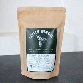 Kraft paper coffee bag with 'Little Birdie' label on a dark surface