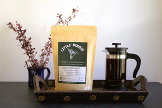 Coffee bag labeled 'Little Birdie' on a tray with a French press and mug.