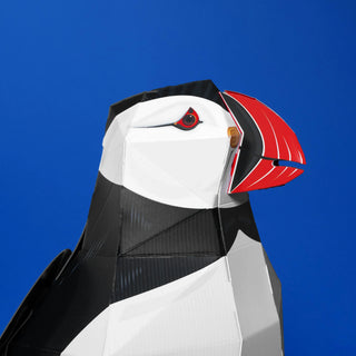 Puffin-shaped construction with black, white, and red colors against a blue background