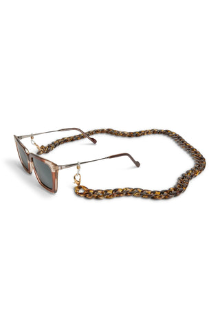 Tortoiseshell glasses chain on a pair of sunglasses against a white background